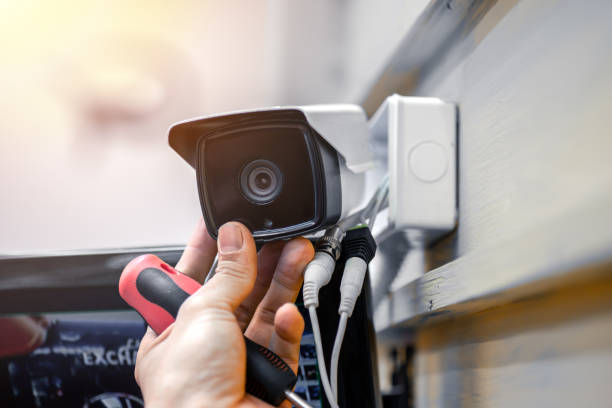 Close-up of surveillance camera installation, male hand holds cctv camera Close-up of surveillance camera installation, male hand holds cctv camera